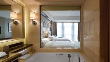 A modern bathroom with a large mirror, a bathtub, and a vanity with a marble countertop.
