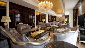 Ein luxuriöses Wohnzimmer mit stilvoller Einrichtung, einem großen Kronleuchter und einem Fernseher.