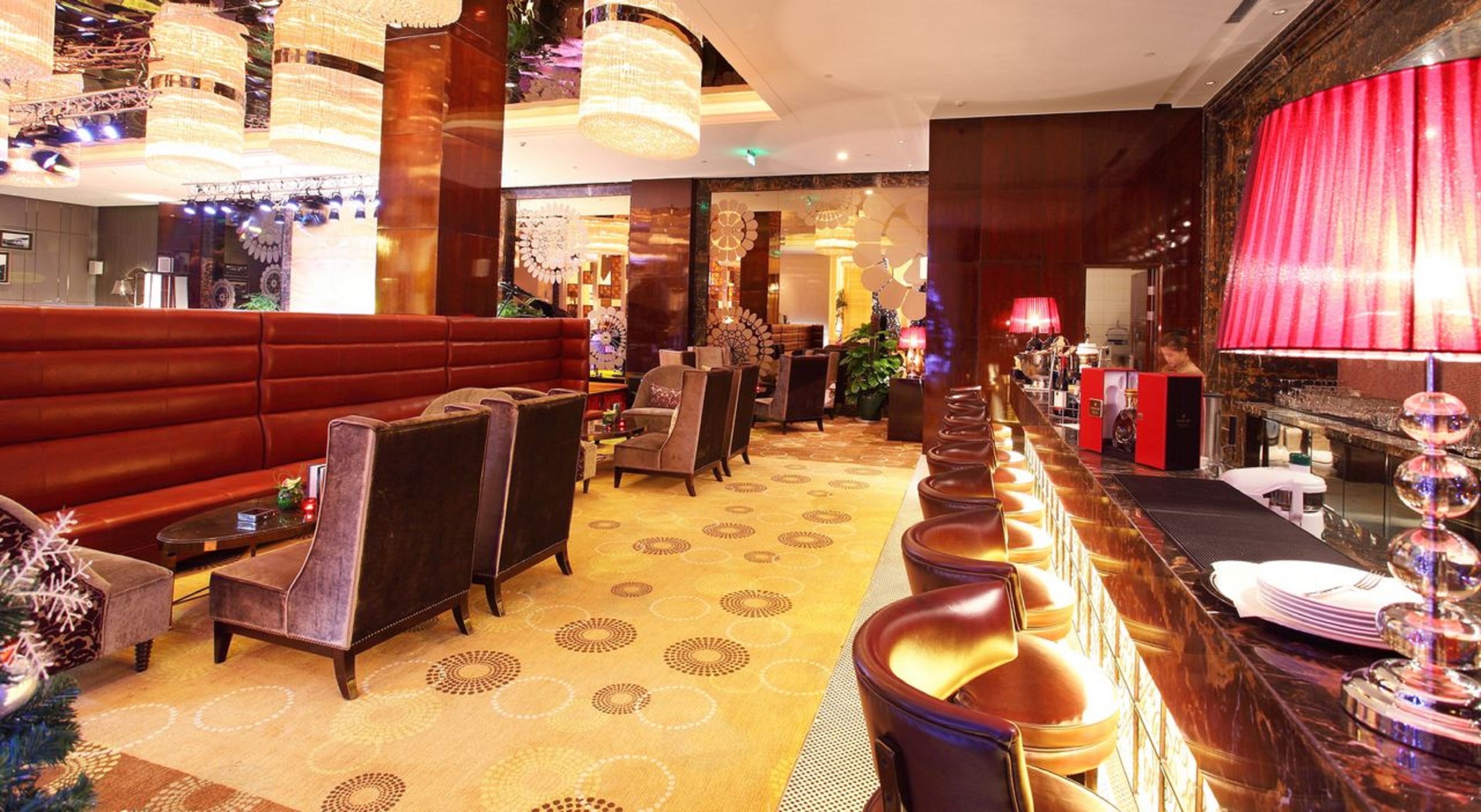Un vestíbulo lujoso con un sofá rojo, varias sillas, una zona de bar e iluminación decorativa.