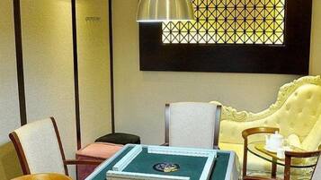 A room with a green table, a yellow sofa, and a window with a geometric pattern.