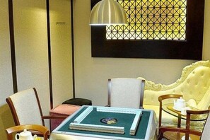 A room with a green table, a yellow sofa, and a window with a geometric pattern. - Sandborg Hotel (Shenzhen)