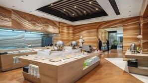 Un moderno vestíbulo de hotel con un mostrador de recepción central, una amplia vitrina de vidrio y un diseño de pared con motivos.