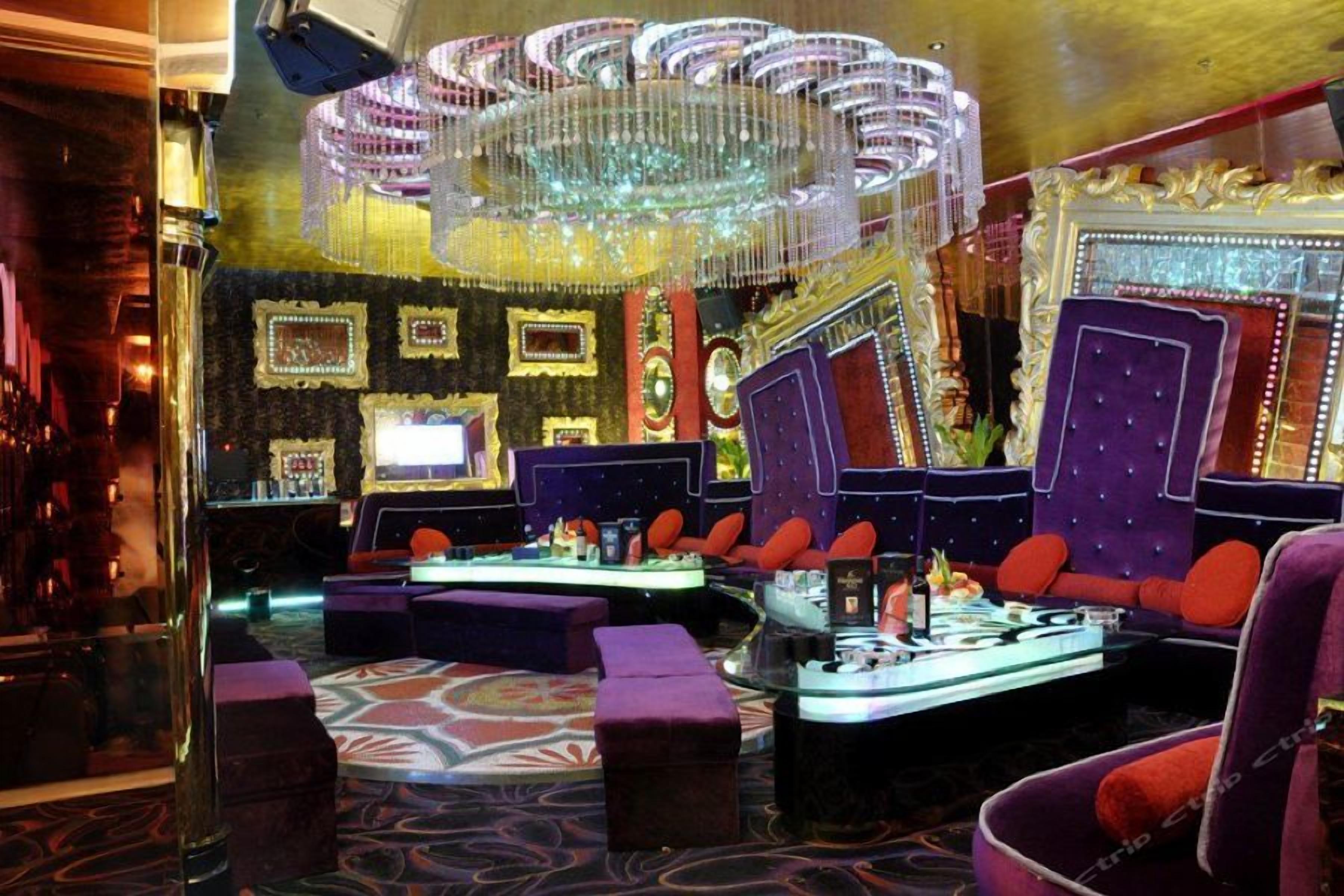 A luxurious lounge area with plush seating, a bar, and a decorative chandelier.