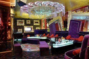 A luxurious lounge area with plush seating, a bar, and a decorative chandelier. - Sandborg Hotel (Shenzhen)