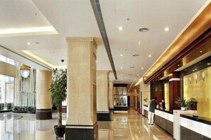 A hotel lobby with a reception desk, a large column, and a plant. - Sandborg Hotel (Shenzhen)