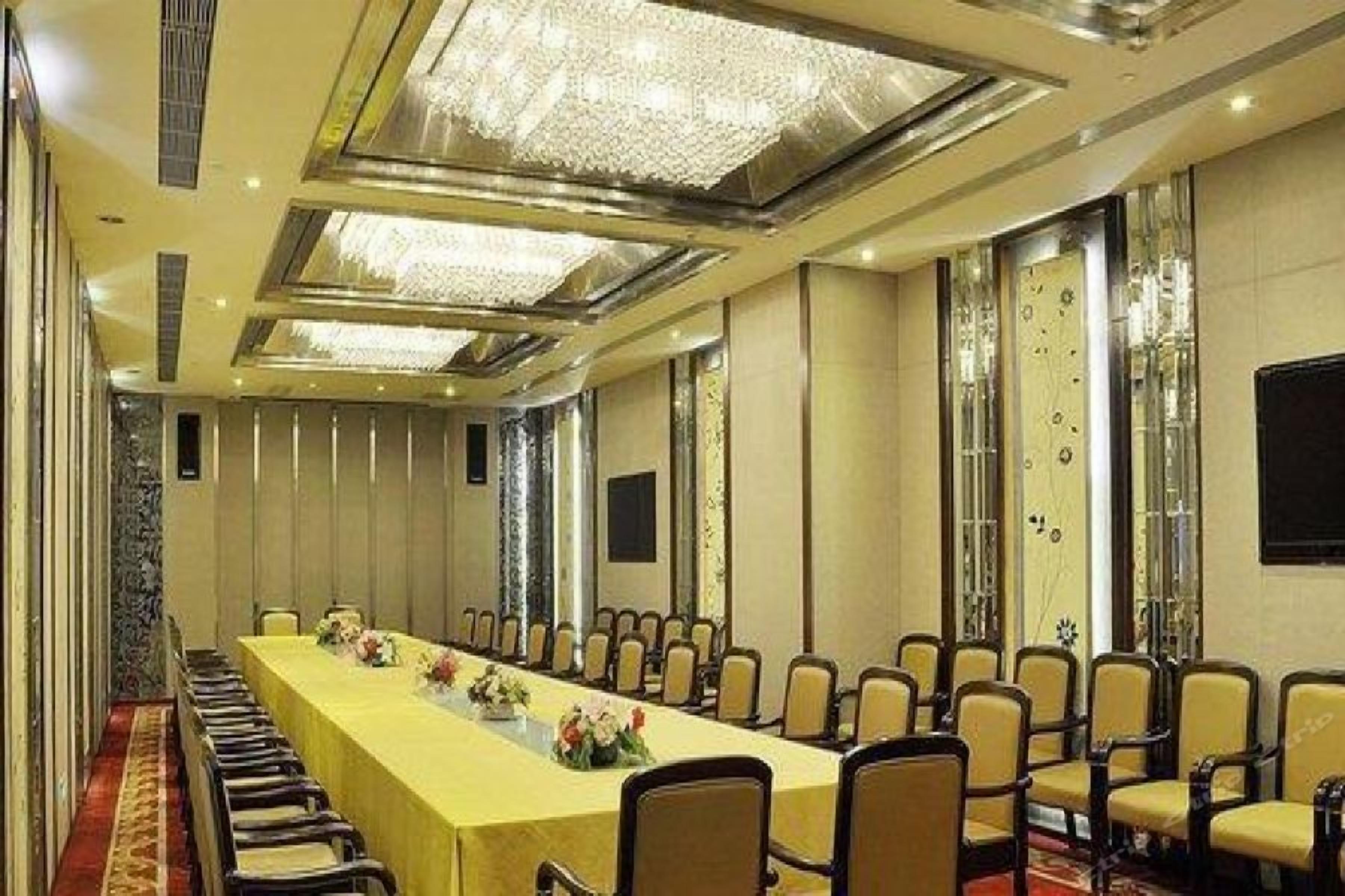 A conference room with a long table and chairs, a chandelier, and a large screen.