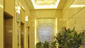 A hallway with a textured wall, potted plants, and a door on the left.