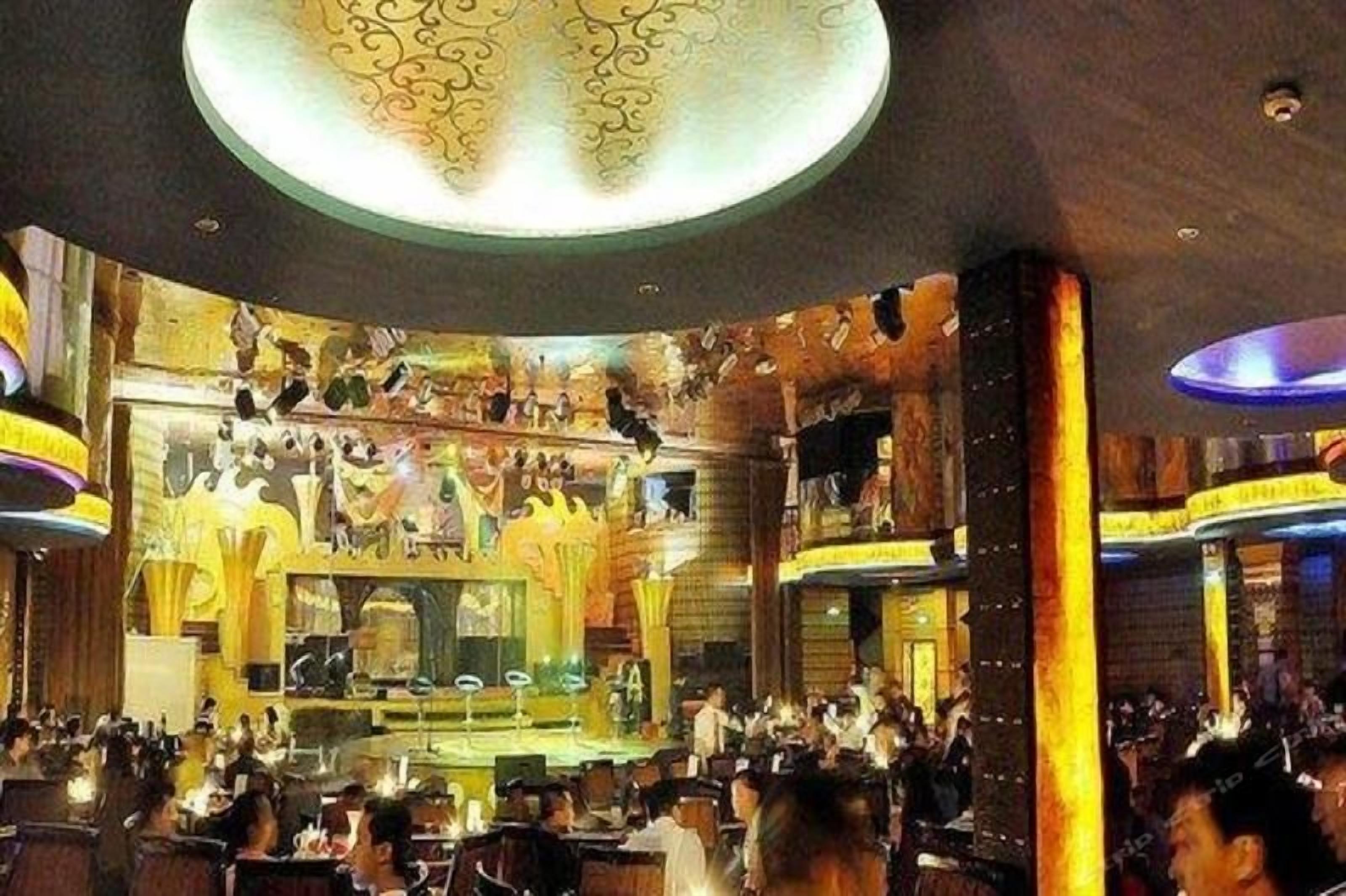 A restaurant with a central stage, multiple dining tables, and a decorative ceiling.