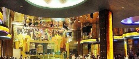 A restaurant with a central stage, multiple dining tables, and a decorative ceiling.