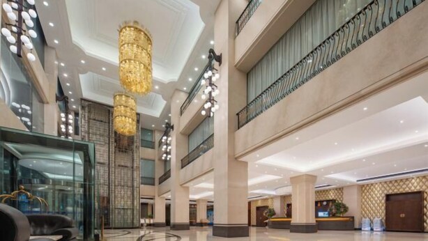 Un vestíbulo espacioso con techo alto, grandes candelabros, un mostrador de recepción y un diseño moderno.