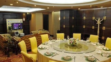 A round dining table with chairs, a television, and a decorative wall panel.