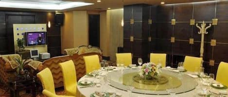 A round dining table with chairs, a television, and a decorative wall panel.