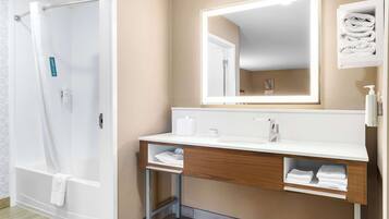 Un baño moderno con ducha, tocador con espejo y un perchero para toallas.