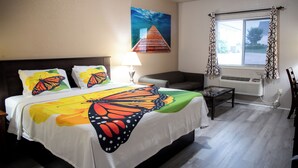 A hotel room with a bed, a nightstand, a lamp, a window with curtains, and a wall painting. - Premium Inn and Suites (Killeen)
