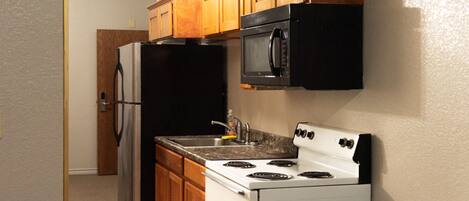 Une cuisine équipée d’un réfrigérateur, d’une cuisinière, d’un four à micro-ondes et de meubles de rangement en bois.