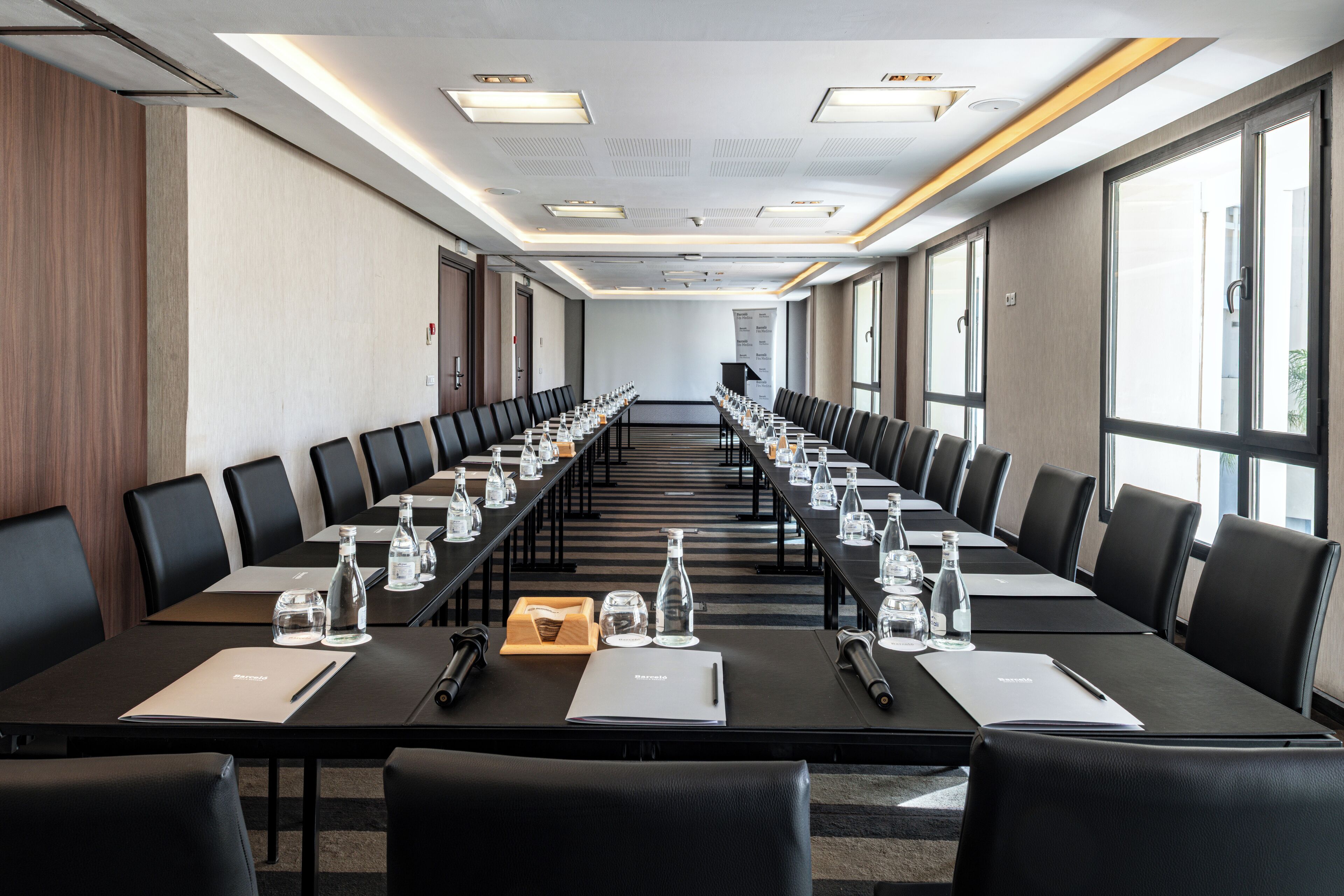 A conference room with long tables, chairs, water bottles, and notepads.