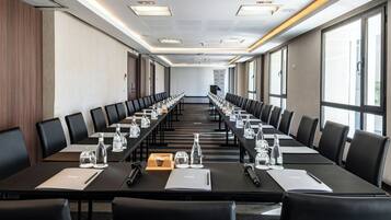 A conference room with long tables, chairs, water bottles, and notepads.
