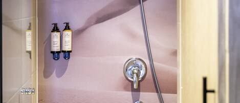A shower with a rain showerhead and two bottles of shampoo.