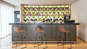 A bar area with a long counter, three stools, and a wall of wine bottles. - Barceló Fès Medina (Fes)