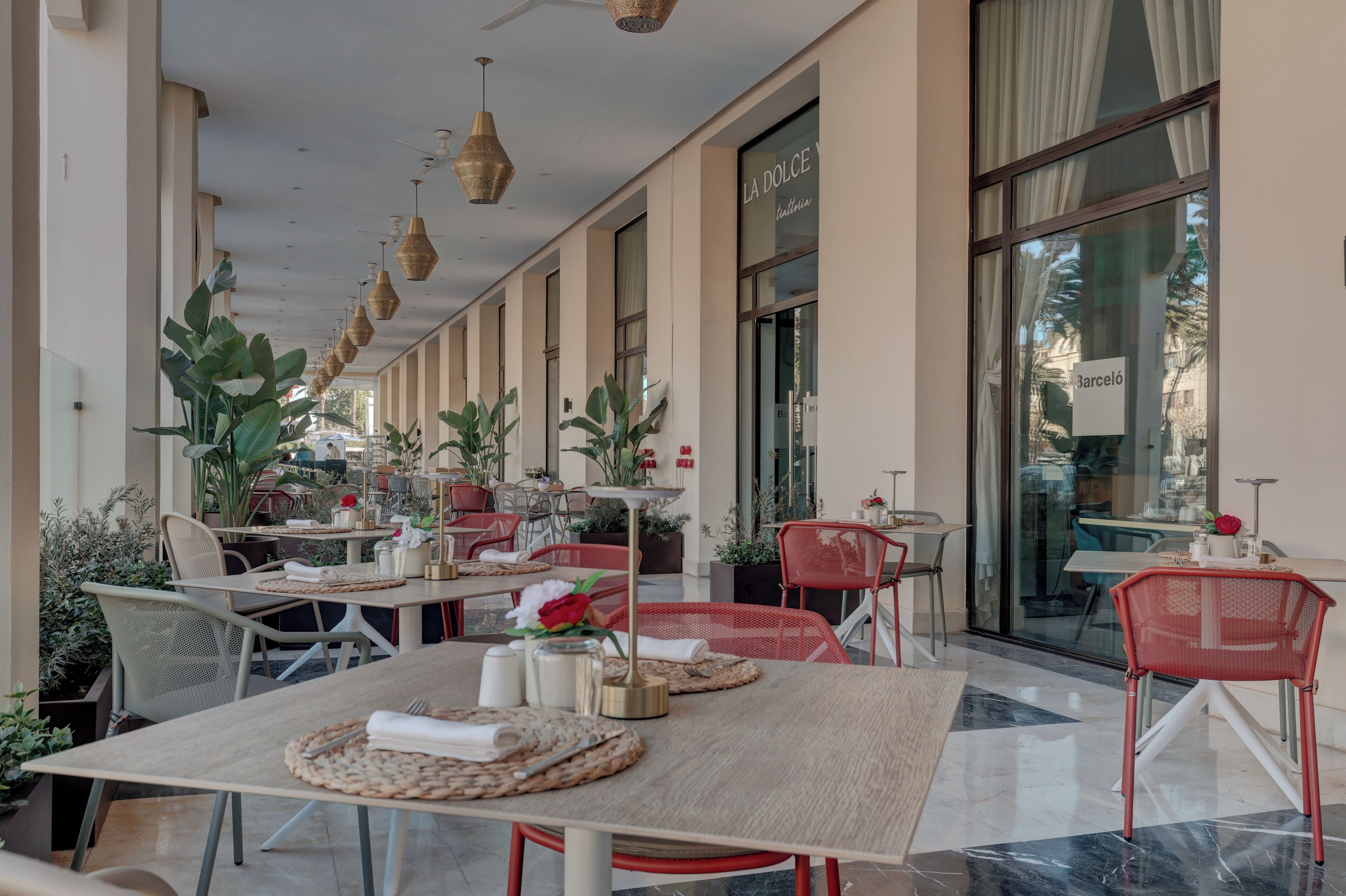 A restaurant with outdoor seating, tables with woven placemats, and potted plants.