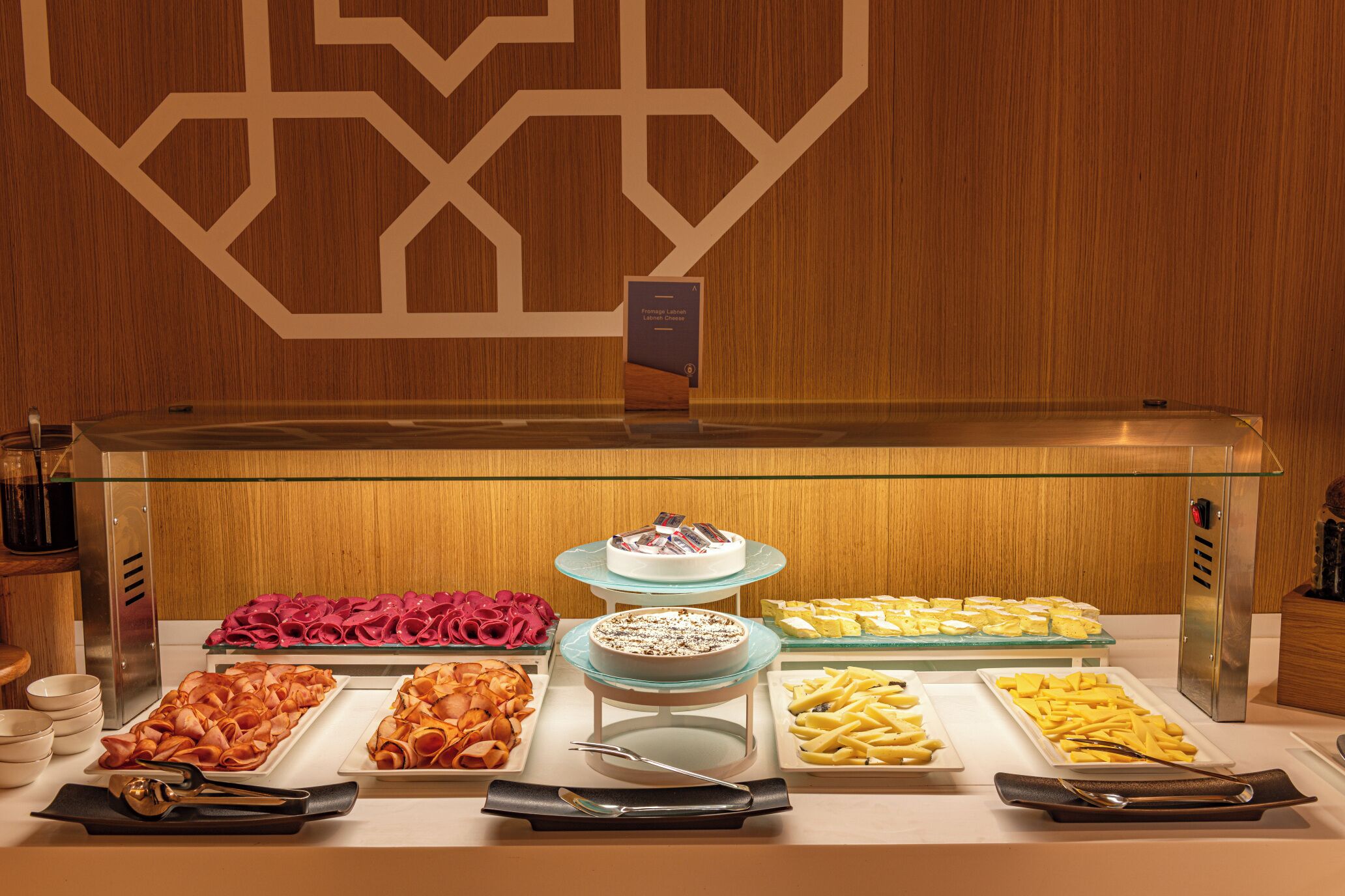 A buffet with various food items including meats, cheeses, and desserts.