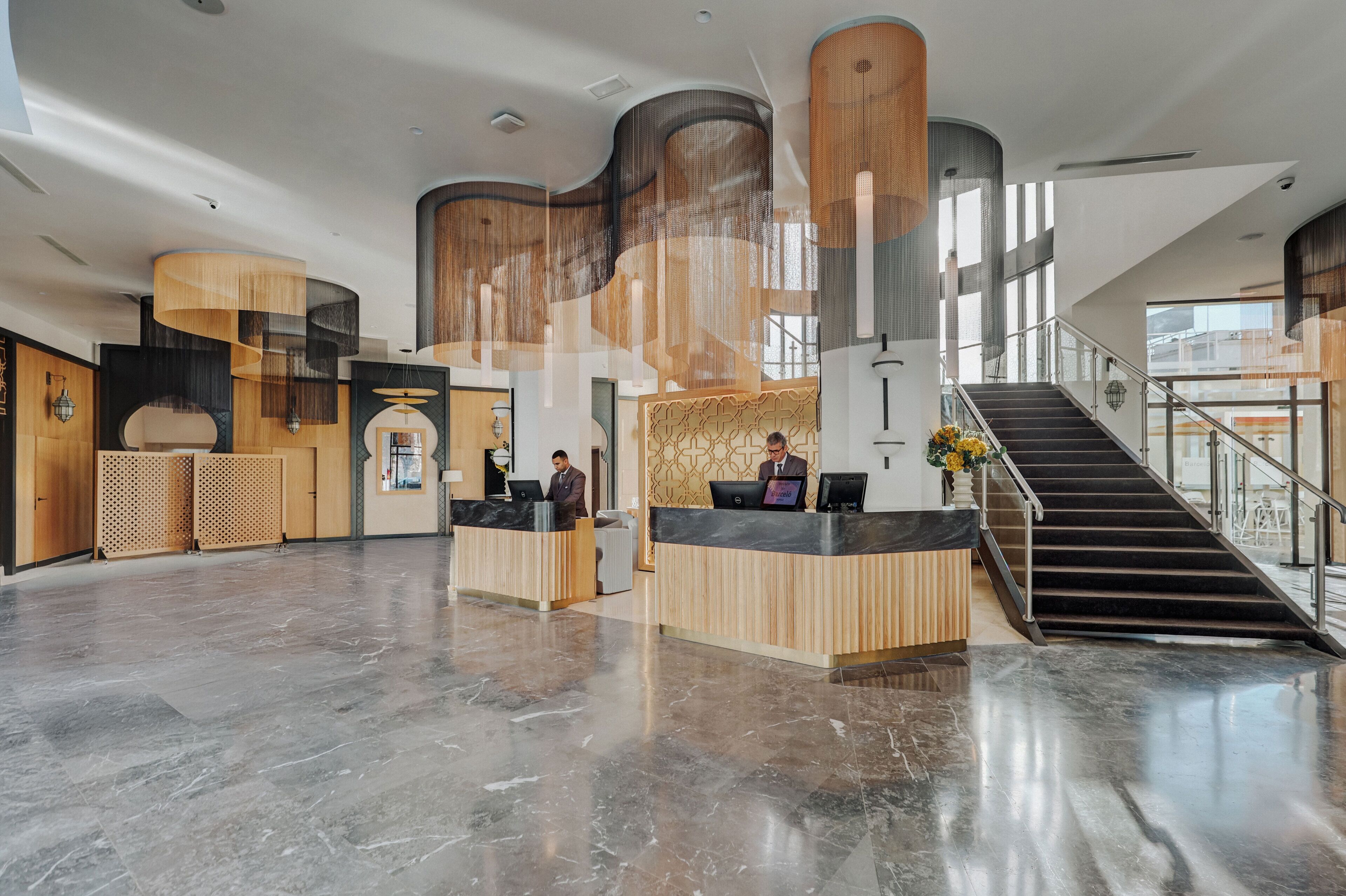 A spacious lobby with a reception desk, a staircase, and a large window providing natural light.