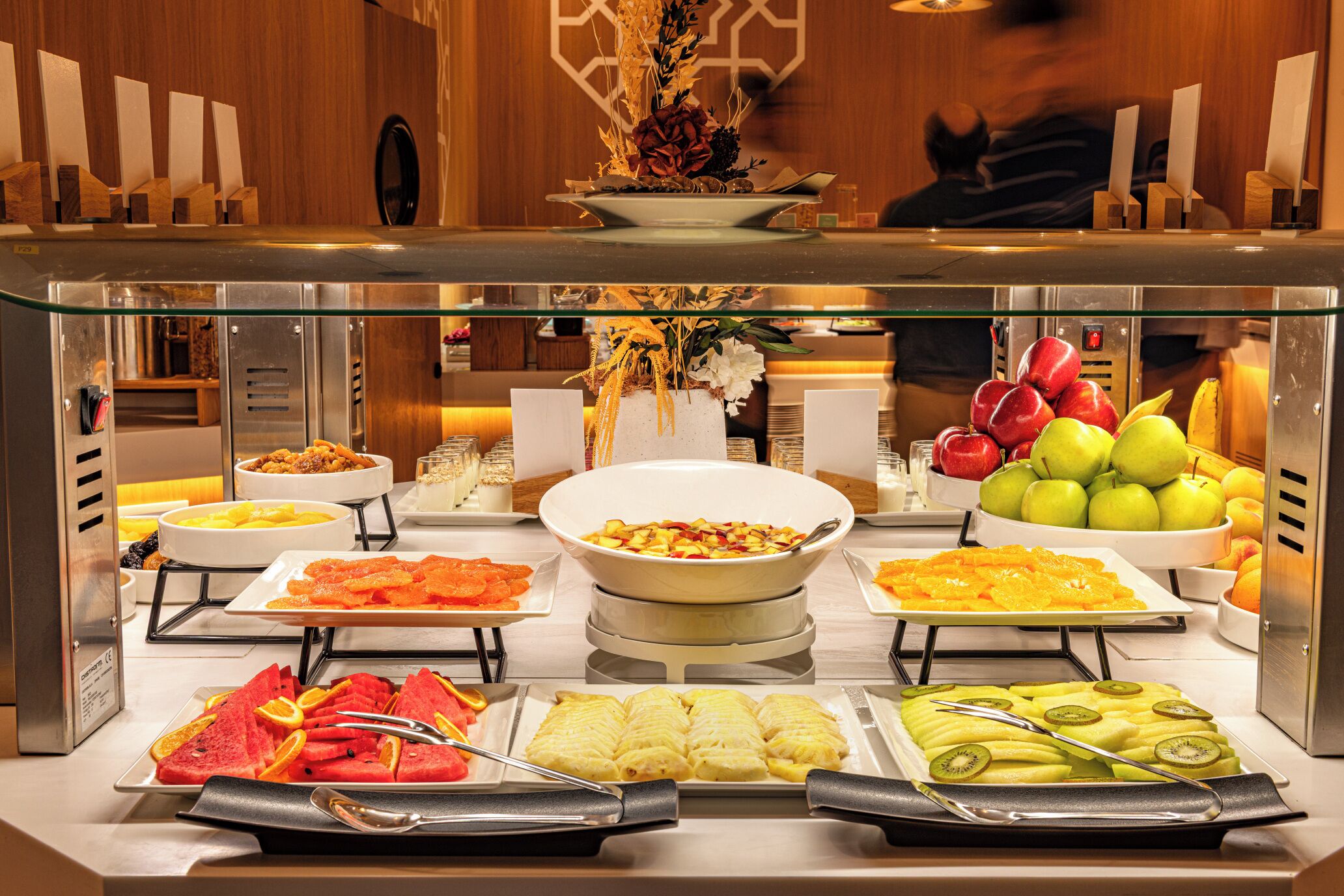 Un bufé con diversos alimentos, incluyendo frutas, pasteles y ensaladas.