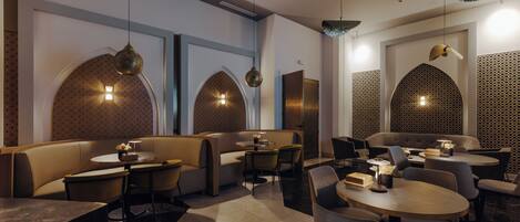 Un interior de restaurante moderno con cabinas, mesas redondas e iluminación colgante.