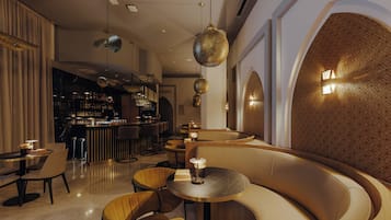 Ein moderner Lounge-Bereich mit einer gebogenen Sitzgruppe, einer Bar im Hintergrund und dekorativer Beleuchtung.