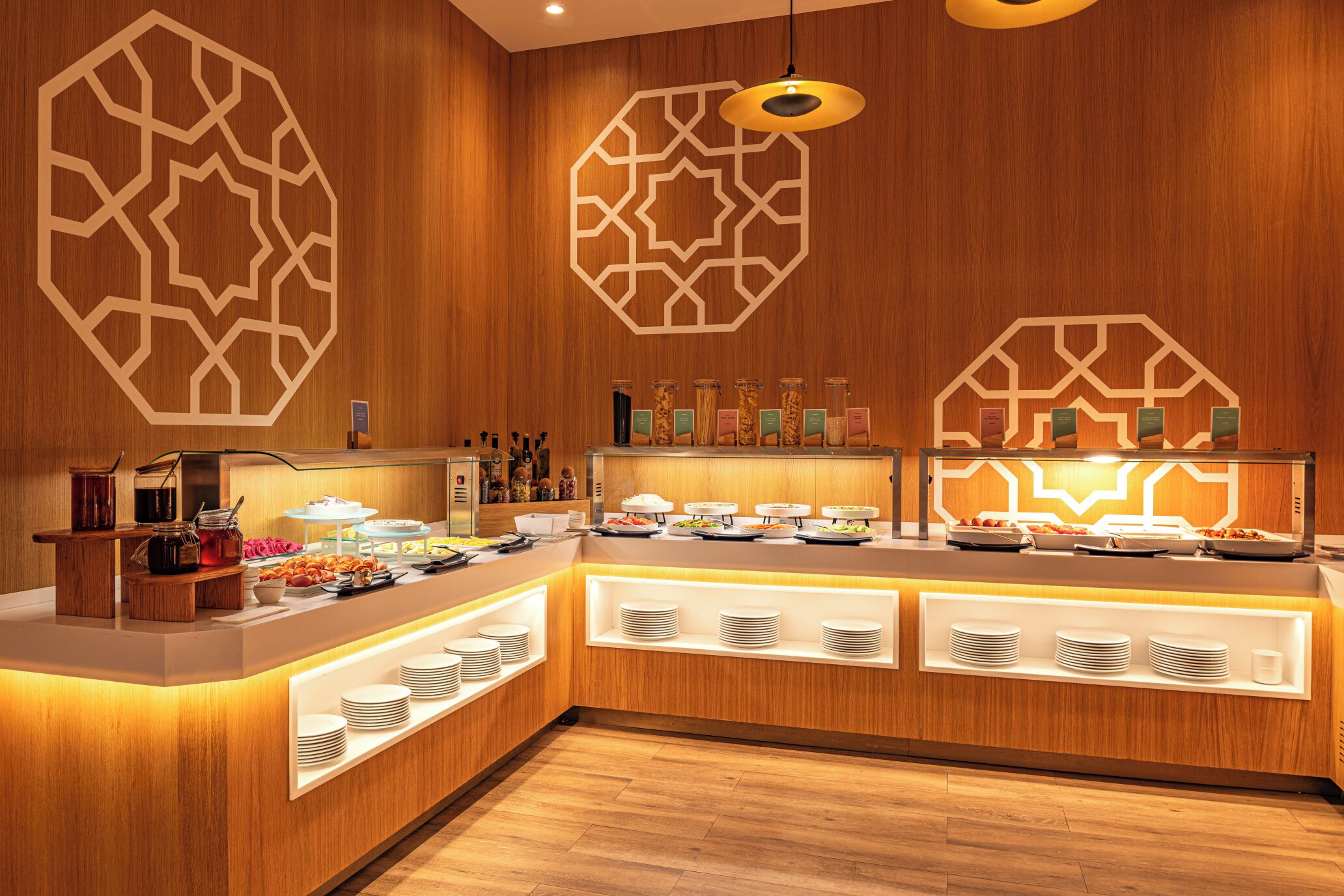 A buffet area with a wooden interior, multiple serving stations, and a geometric wall design.