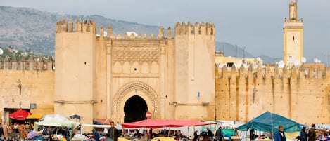 Un edificio histórico con un gran arco y un minarete al fondo.