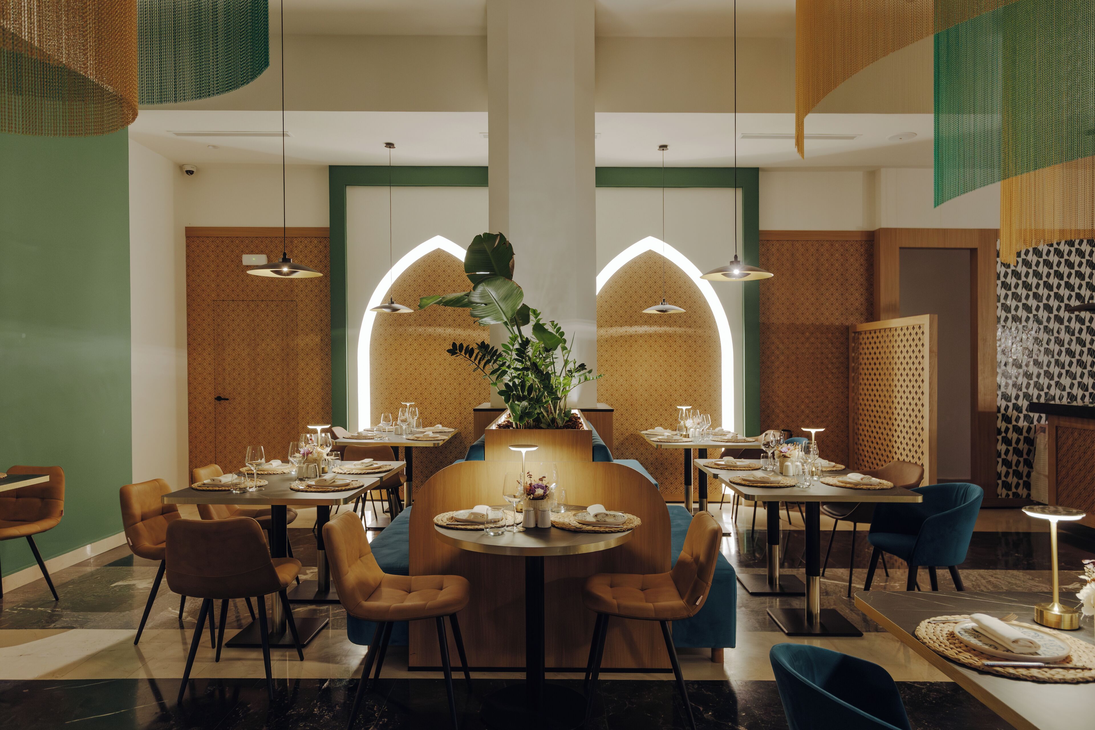 A restaurant with round tables, chairs, and a central plant.