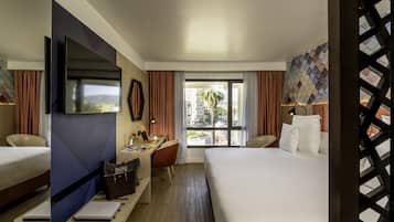 Habitación de hotel con dos camas, un escritorio, un televisor y vistas a la ciudad.