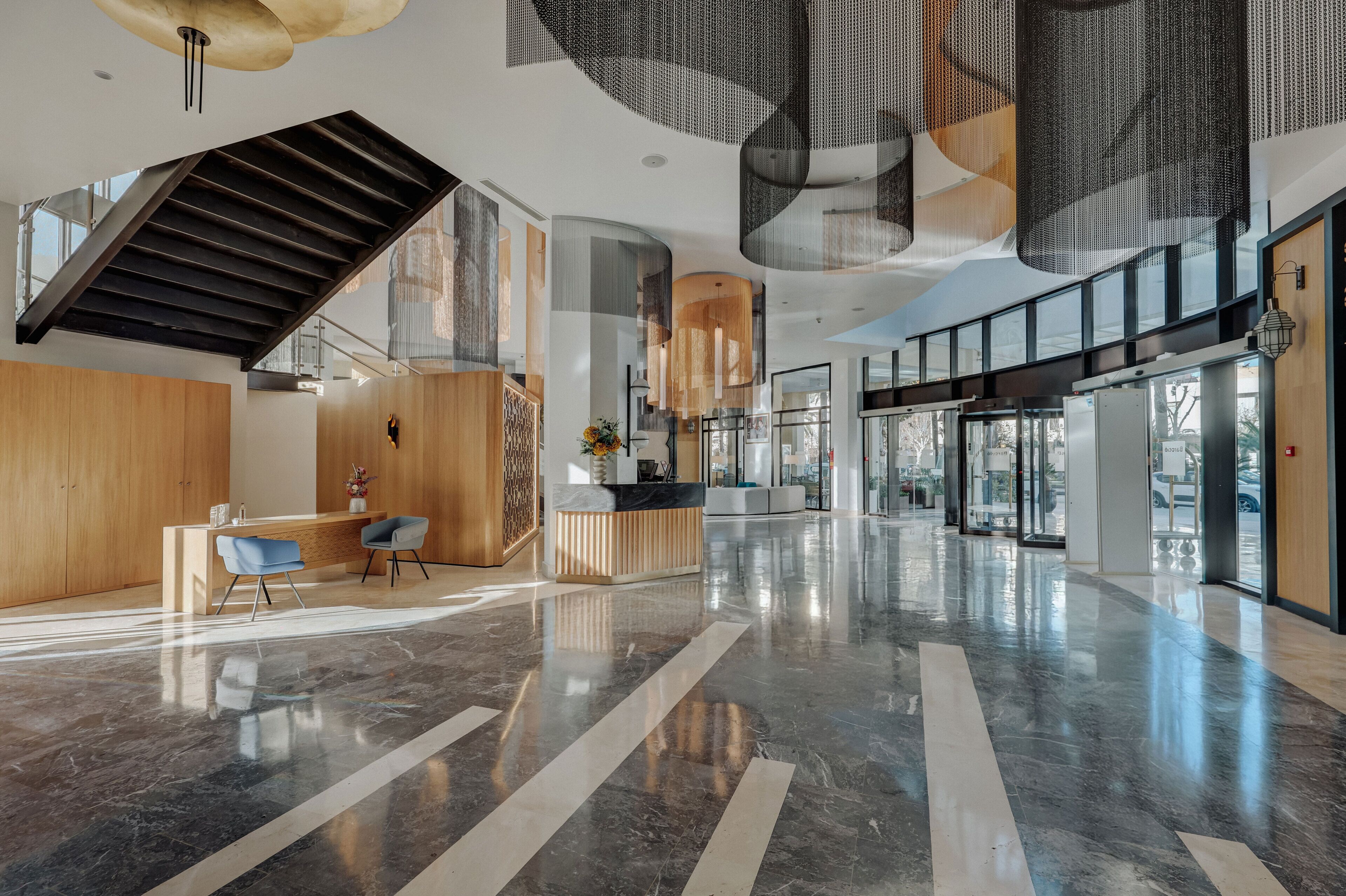 A spacious lobby with a reception desk, seating area, and a staircase.