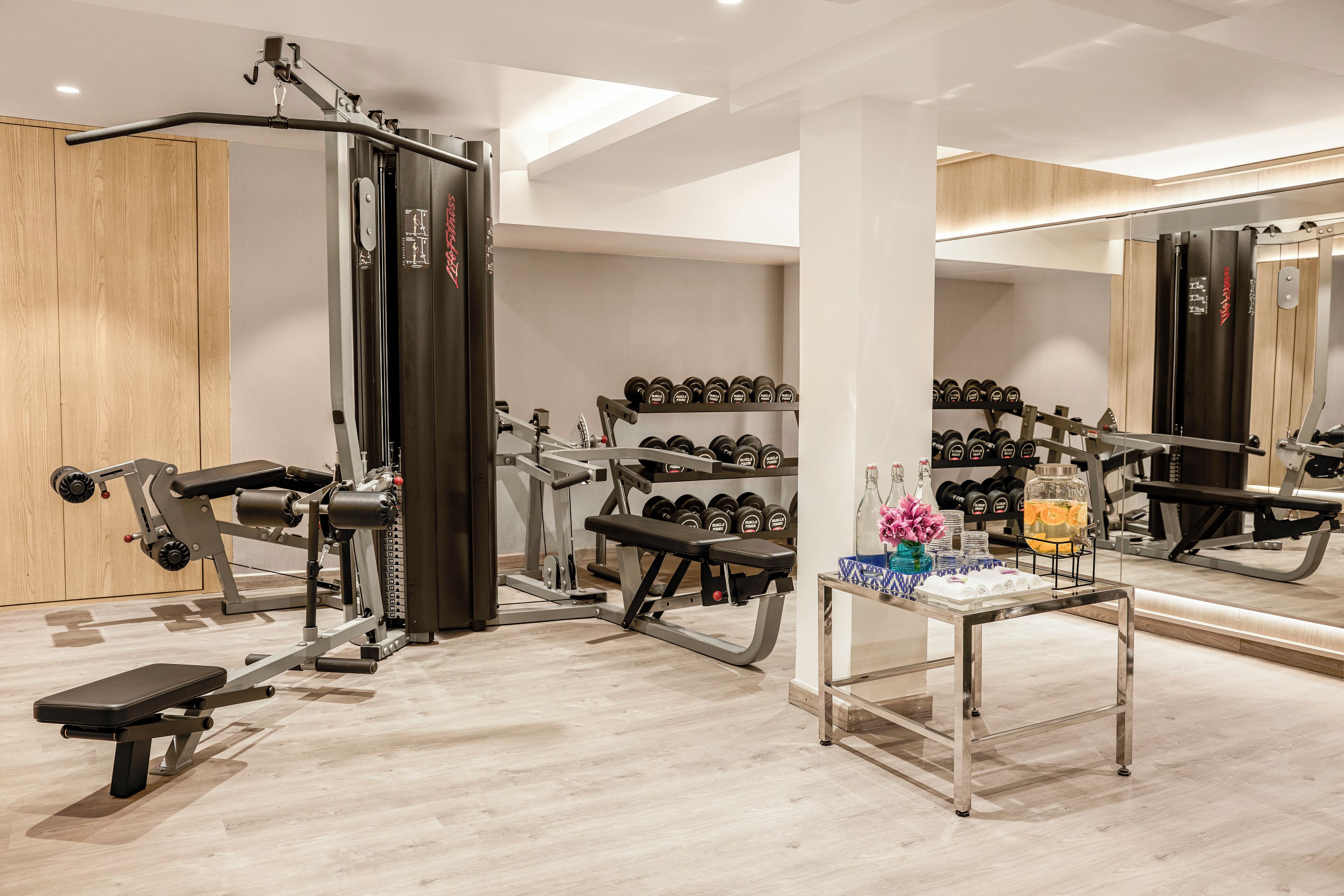 A gym with weight machines, dumbbells, and a bench.