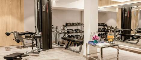 A gym with weight machines, dumbbells, and a bench.