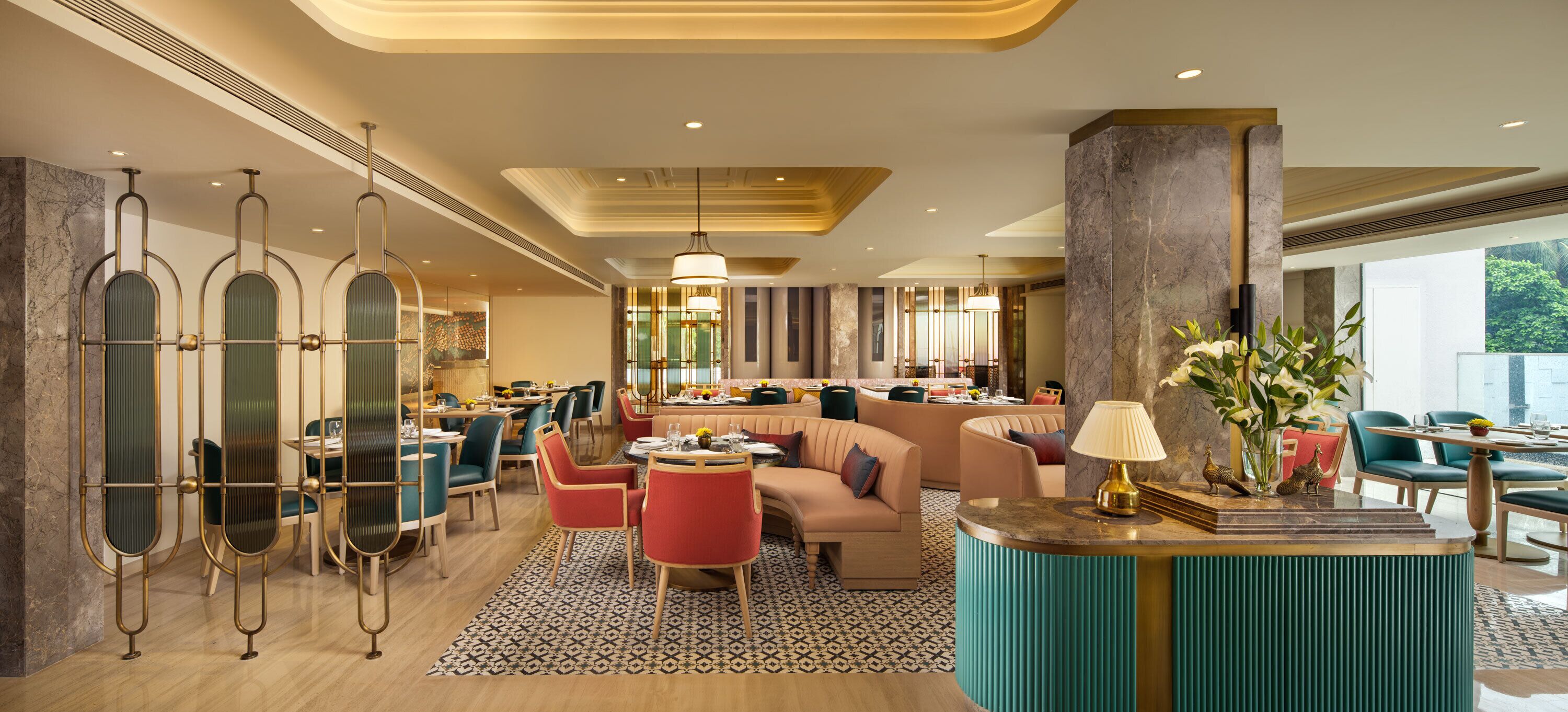 A modern hotel lobby with a seating area, a reception desk, and a dining space.