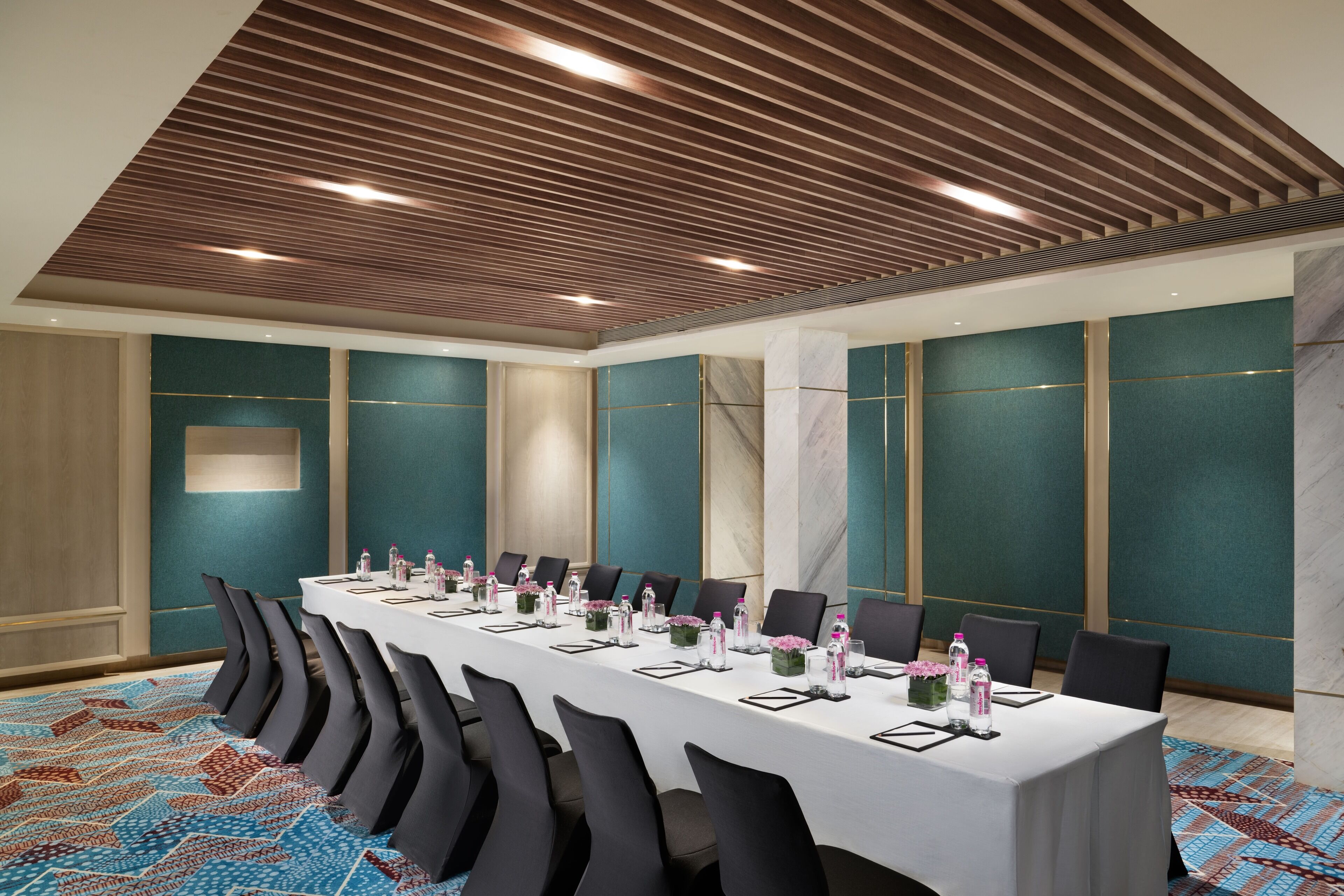 A conference room with a long table, chairs, and a patterned carpet.
