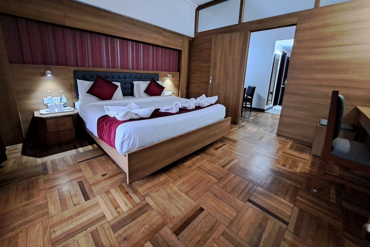 A modern hotel room with a wooden bed, headboard, and nightstands.
