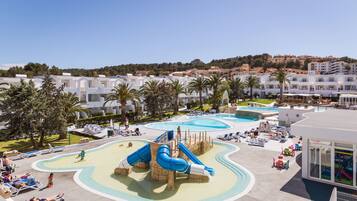 Relax by the pool surrounded by a water park with a large slide and a smaller one, offering a scenic view of the surrounding landscape.