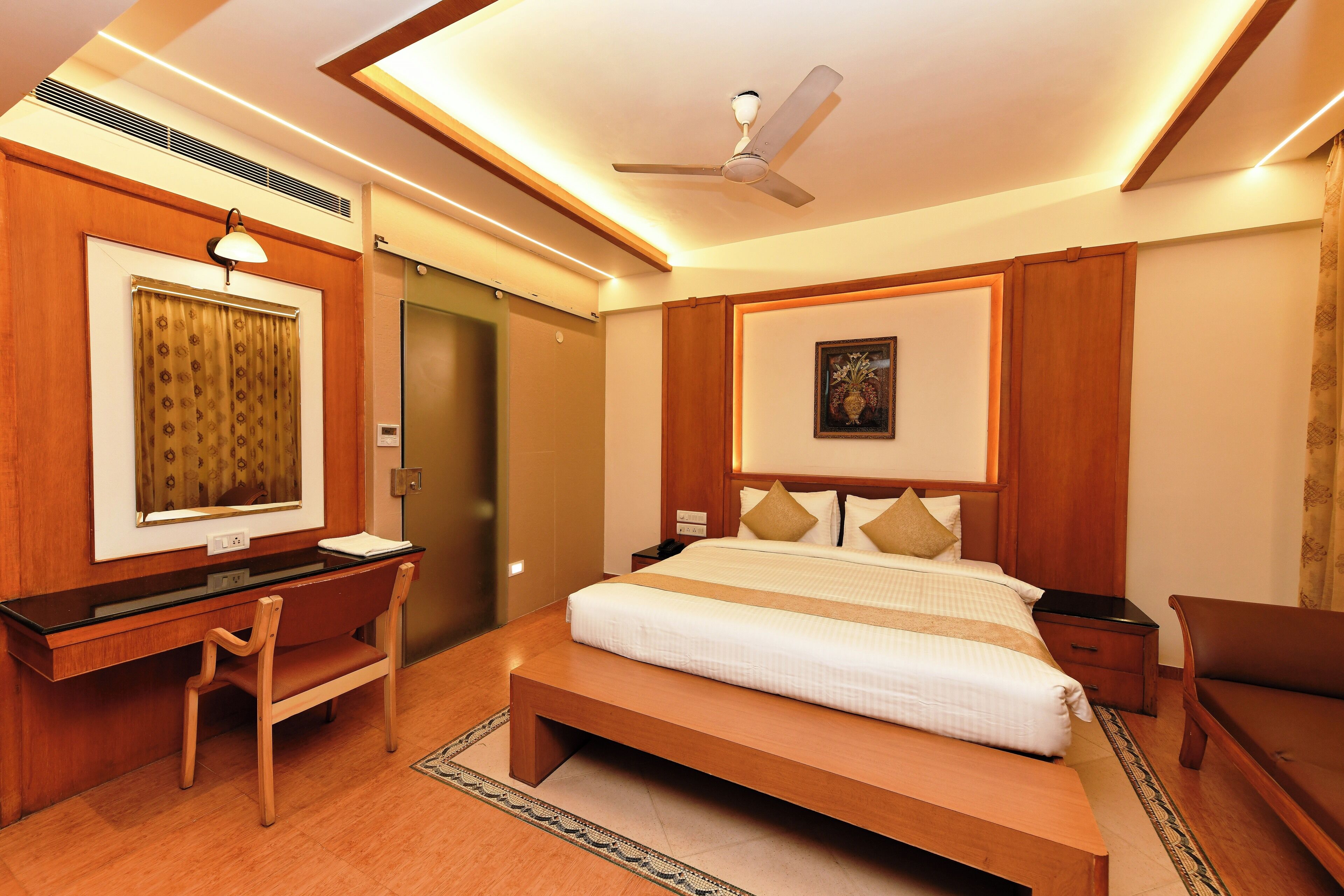 A hotel room with a bed, desk, chair, and a ceiling fan.