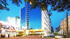 Un hôtel doté d’une façade moderne en verre, d’une tour verticale imposante et d’un hall d’entrée bien éclairé, agrémenté d’une enseigne.