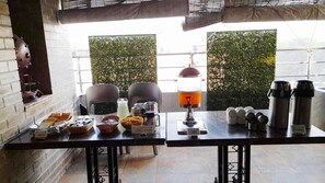A breakfast setup with a table, coffee maker, and various food items.