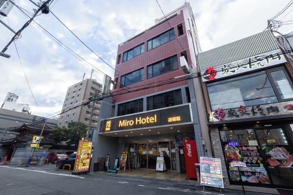 Un hotel con fachada moderna, señalización que indica 'Miro Hotel' y una entrada visible.