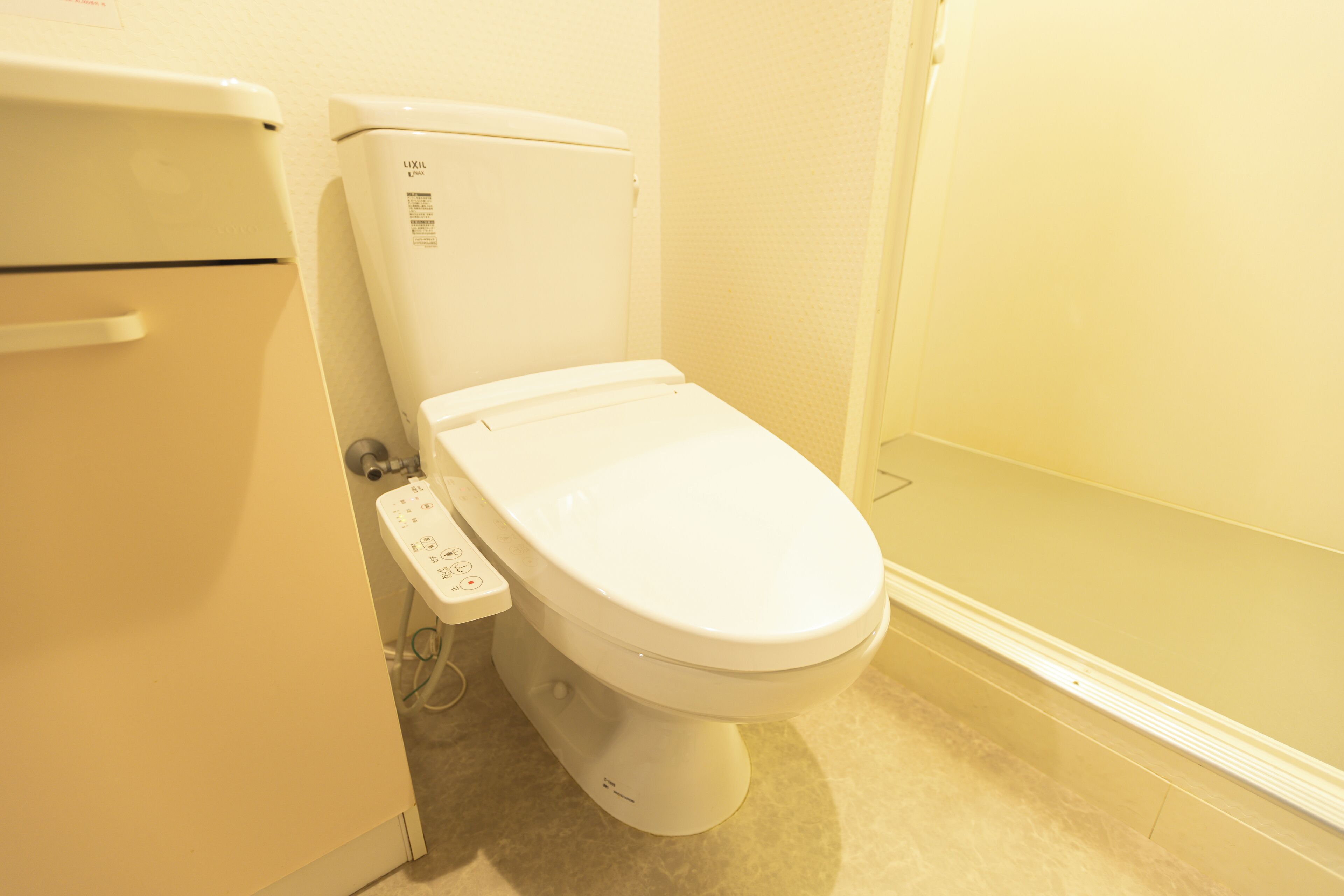 Een wit toilet met bedieningspaneel en toiletrolhouder.