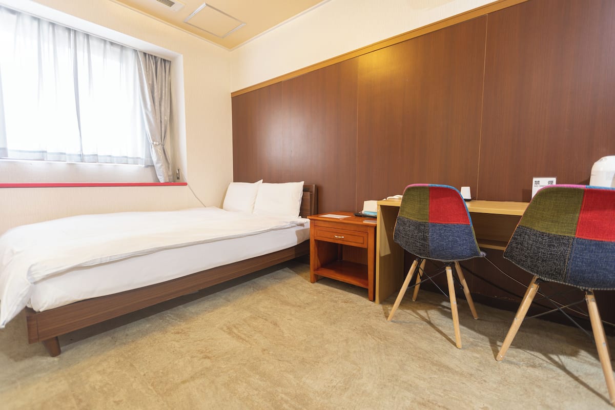 Una habitación de hotel con una cama, un escritorio y una silla.