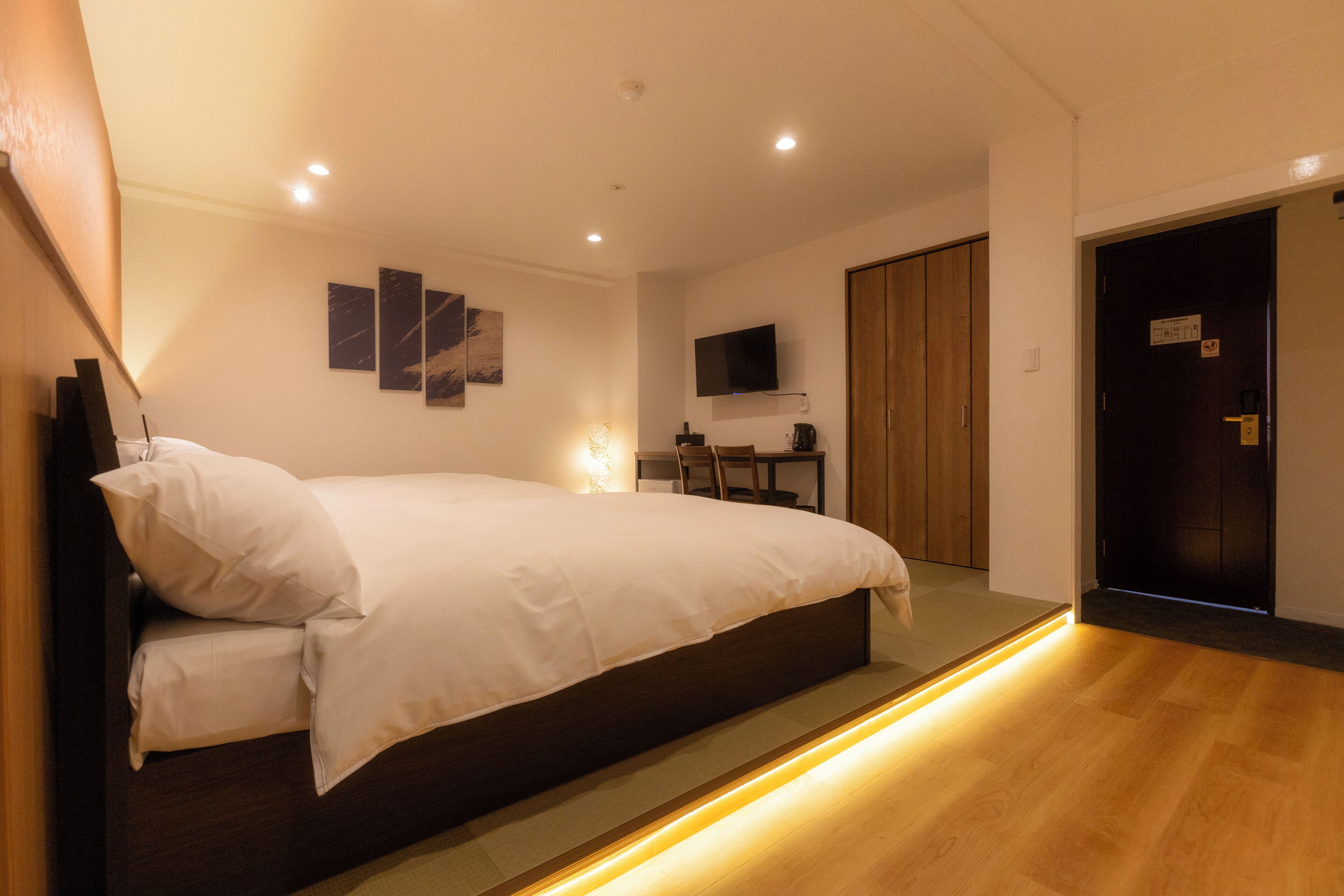 Una camera da letto moderna con un letto grande, una scrivania e una TV a muro.