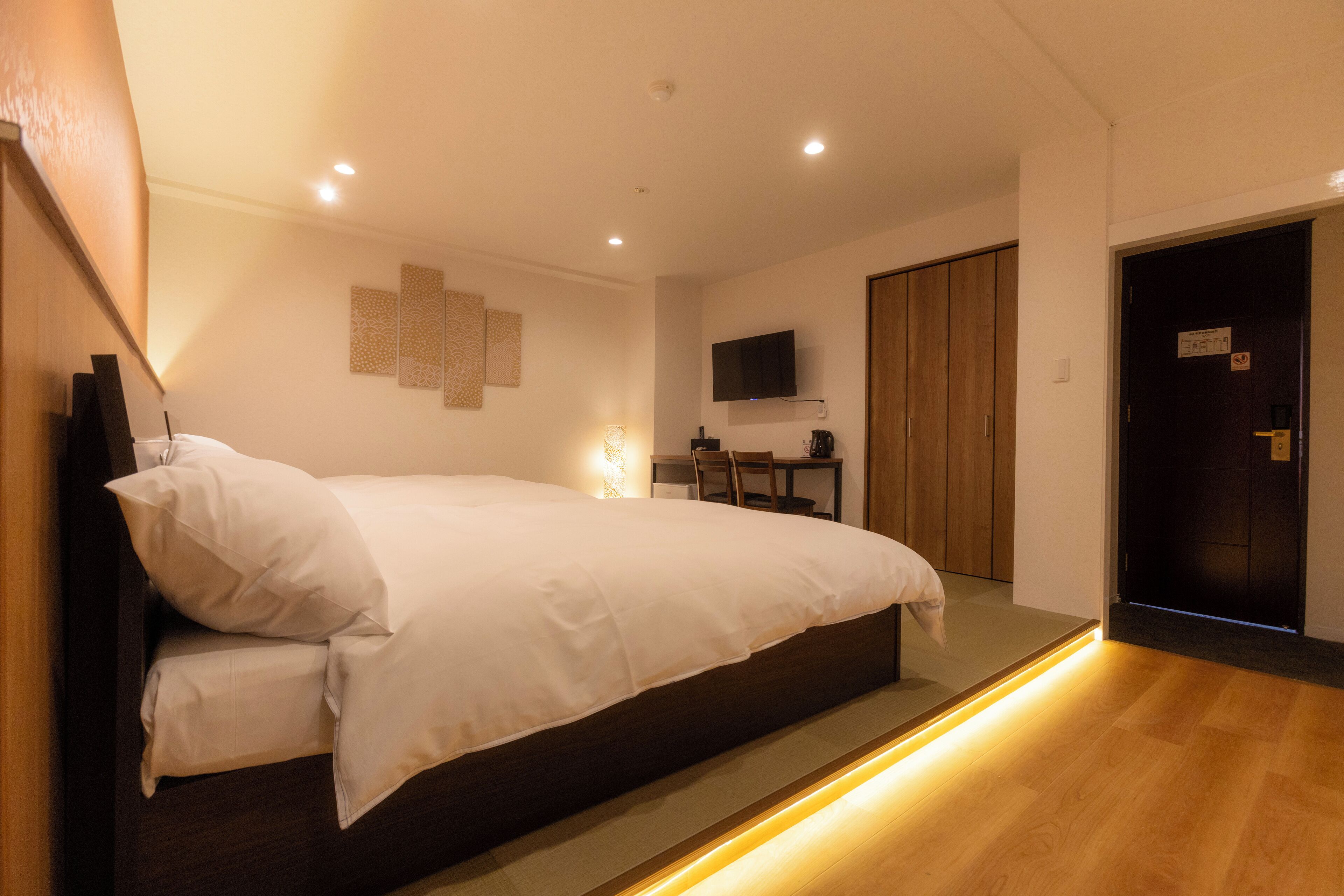 Quarto moderno com uma cama grande, uma TV de tela plana na parede e um guarda-roupa de madeira.