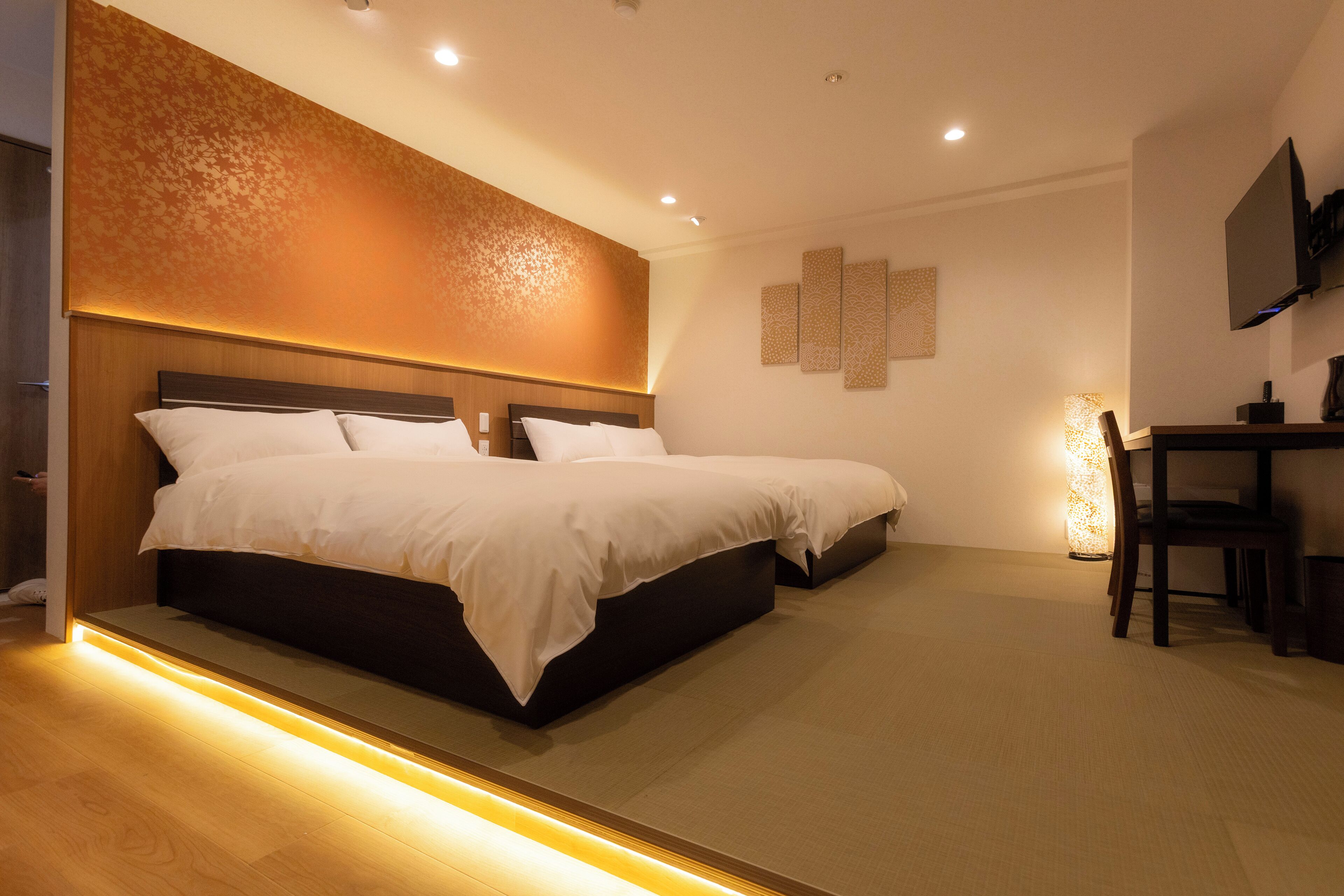 A modern hotel room with a large bed, a desk, and a TV.
