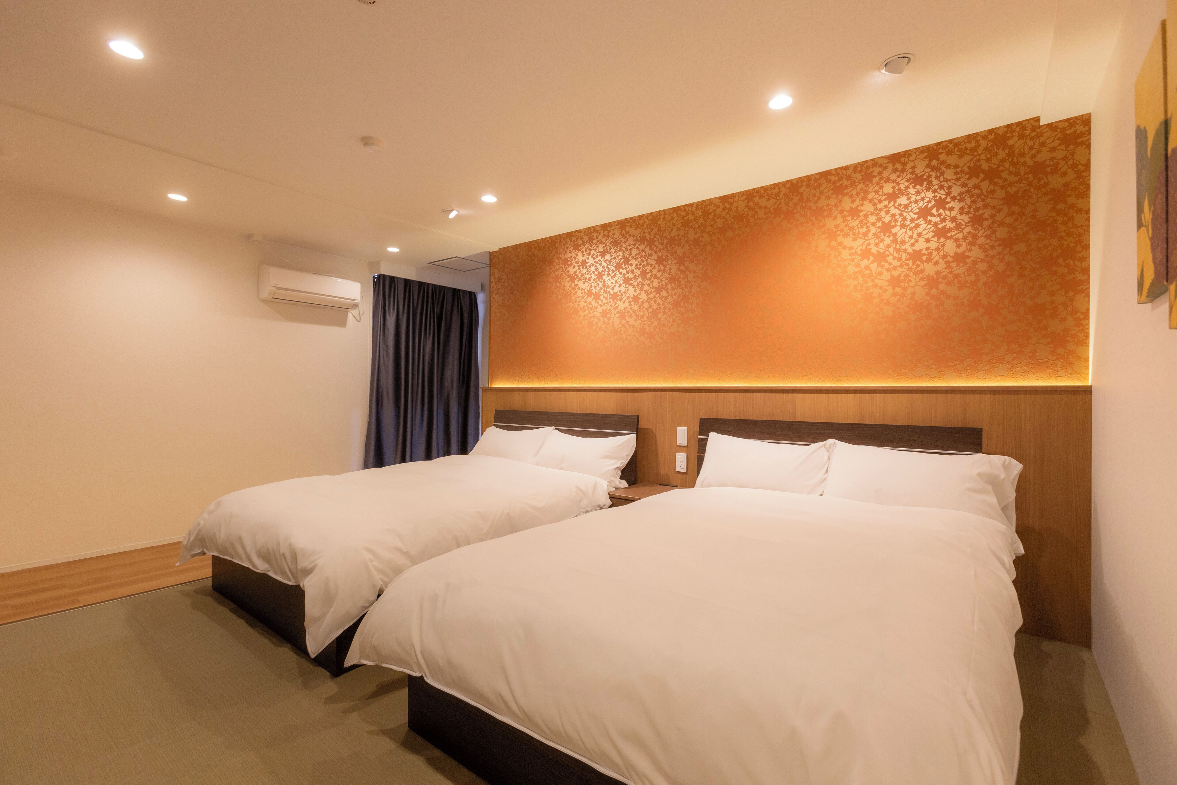 Ein Hotelzimmer mit zwei Betten, einem Holzkopfteil, einer Klimaanlage und einer Wand mit Muster.